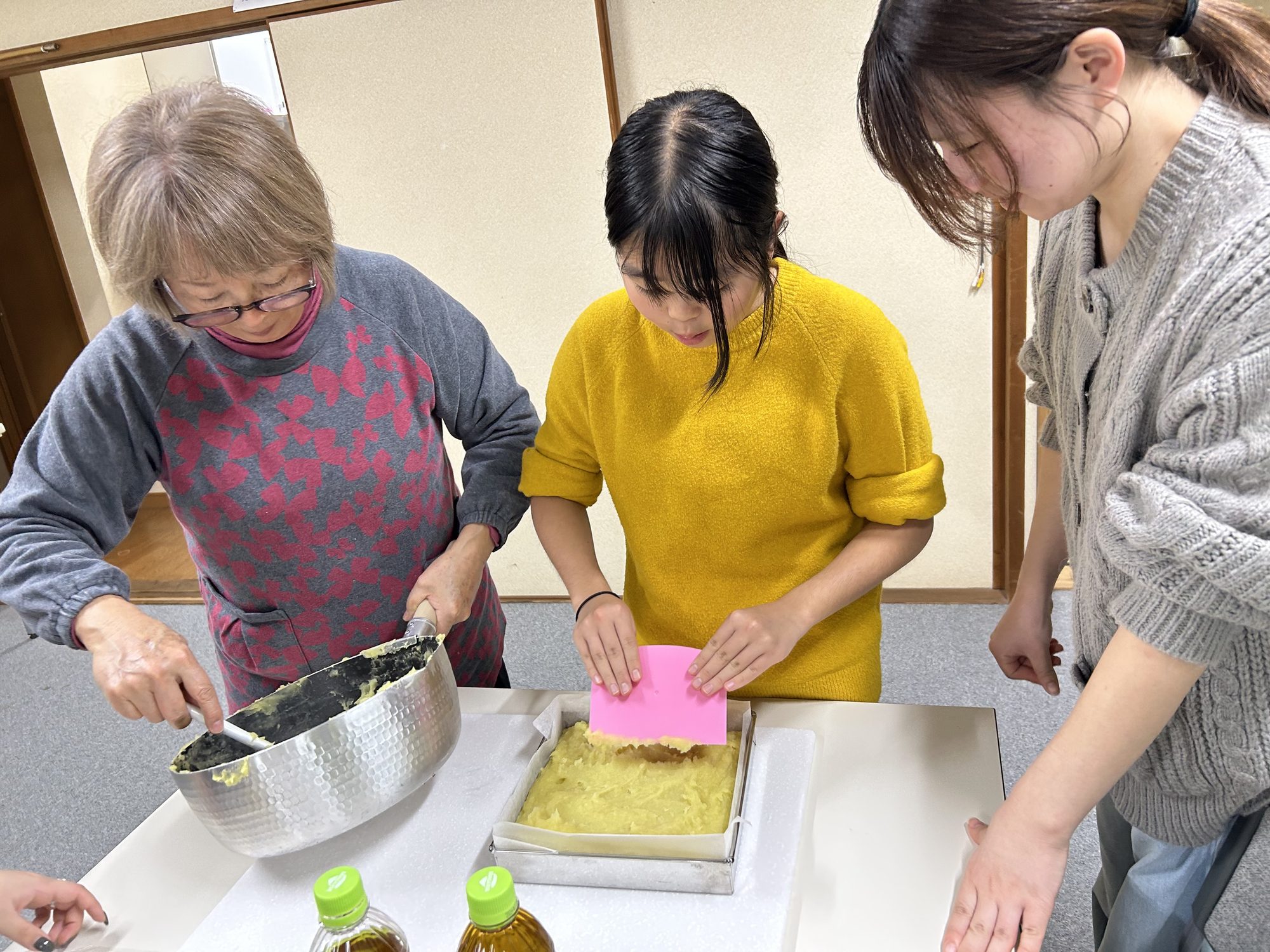 松下さんと大学生団体とらいくが芋羊羹を型に詰める事前試作の様子